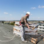 Heizungsbaumeister Lars Ost prüft auf dem Dach die gerade angelieferten Bauteile für die Solaranlage.