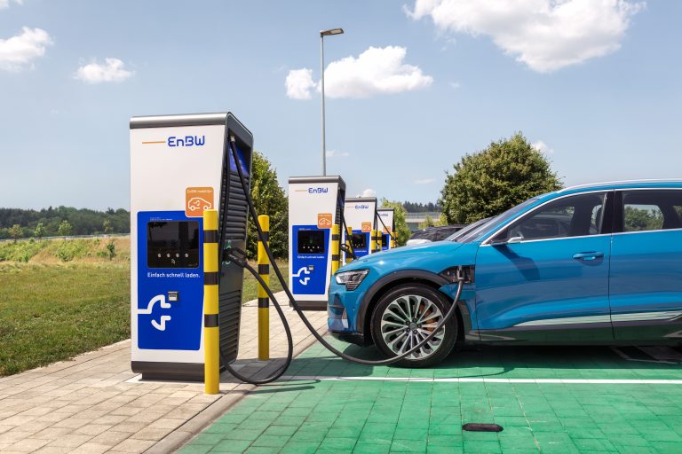 Das Bild zeigt mehrere Schnellladestationen. Im Vordergrund wird ein Fahrzeug geladen.