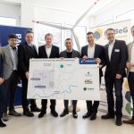 Gruppenfoto von acht Personen bei der Vorstellung des geplanten Windparks Schäferköppel. Von links: Tina Zapf Rodriguez (Frankfurter Dezernentin für Klima, Umwelt und Frauen), Thomas Schrage (Erster Stadtrat Karben), Dr. Michael Maxelon (Vorstandsvorsitzender Mainova AG), Dr. Oliver Jedynak (Bürgermeister Bad Homburg vor der Höhe), Mike Josef (Oberbürgermeister Frankfurt am Main), Martin Giehl (Vorstand Technik & Erzeugung Mainova AG), Christian Stenglein (Vorstandsmitglied FraBeG) und Yannick Schwander (Ortsvorsteher Nieder-Erlenbach). Die Gruppe hält eine große Standortkarte des Windparks; im Hintergrund stehen Roll-ups der beteiligten Organisationen und ein Modell eines Windrads.