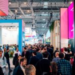 Messehalle der E-world 2026 in Essen mit dichtem Besucherandrang: Zahlreiche Fachbesucherinnen und Fachbesucher gehen durch breite Gänge zwischen hohen, farbig beleuchteten Messeständen, während große Displays und Banner zu Energie- und Speicherlösungen informieren.
