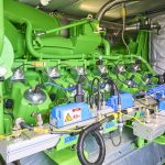 Detailansicht einer Kraft-Wärme-Kopplungsanlage mit grünem Gasmotor, Zylindern, Zündmodulen und Verkabelung in einem Technikraum.