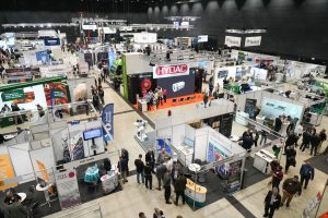 Blick von oben in eine Messehalle der GeoTHERM in Offenburg: Zahlreiche Aussteller präsentieren an hell beleuchteten Ständen Bohrtechnik, Geothermie- und Energielösungen, während Fachbesucherinnen und Fachbesucher zwischen den Ständen Gespräche führen.