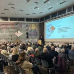 Alt-Text: Bürgerversammlung der Stadt Leverkusen zur kommunalen Wärmeplanung: Zahlreiche Bürgerinnen und Bürger sitzen in einem Veranstaltungsraum und verfolgen einen Vortrag auf einer großen Leinwand, auf der „Heizen mit Zukunft“ präsentiert wird.