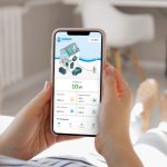 Eine Person hält ein Smartphone in der Hand und nutzt die App „Kilowatt.Käpt’n“ der WEMAG. Auf dem Display sind Energiedaten eines Haushalts zu sehen, darunter Stromproduktion, Verbrauch, Batteriespeicher und Einspeisung. Die App dient zur digitalen Steuerung von Eigenverbrauch und Energieflüssen im Zuhause.