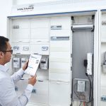 Techniker mit Tablet vor geöffnetem Zählerschrank bei der Inbetriebnahme eines intelligenten Messsystems mit digitalen Stromzählern.