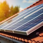 Mehrere Photovoltaikmodule sind auf dem geneigten Ziegeldach eines Wohnhauses installiert. Die Solaranlage wird von Sonnenlicht angestrahlt, während im Hintergrund unscharf Bäume und ein blauer Himmel zu sehen sind. Das Bild symbolisiert die dezentrale Erzeugung von Solarstrom und die Nutzung erneuerbarer Energien im privaten Haushalt.