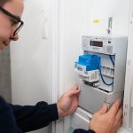 Ein Techniker installiert ein intelligentes Messsystem (Smart Meter) in einem Stromzählerkasten. Das digitale Messgerät mit Kommunikationsmodul wird in die bestehende Strominfrastruktur eingebaut und ermöglicht die automatische Erfassung und Übermittlung von Verbrauchsdaten.