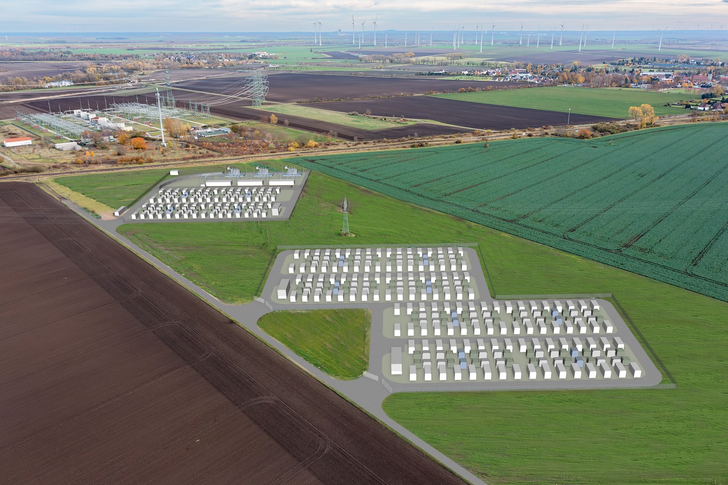 Luftaufnahme einer ländlich geprägten Landschaft mit Feldern, Windkraftanlagen und einem Umspannwerk. In die Aufnahme ist eine Visualisierung eines großflächigen Batteriespeichers eingebettet: Mehrere Reihen von Speichercontainern und technische Anlagen sind auf zwei Arealen dargestellt, die über Straßen miteinander verbunden sind. Das Bild zeigt die geplante Integration eines Batterie-Großspeichers in die bestehende Energieinfrastruktur zur Speicherung und Bereitstellung von erneuerbar erzeugtem Strom.