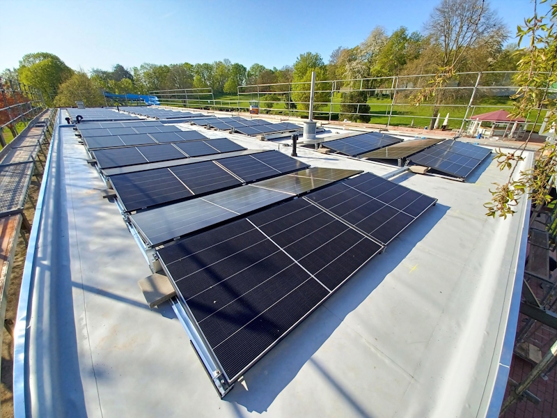 Photovoltaikanlage mit zahlreichen Solarmodulen auf dem Flachdach des Freibads der Stadt Alzey.